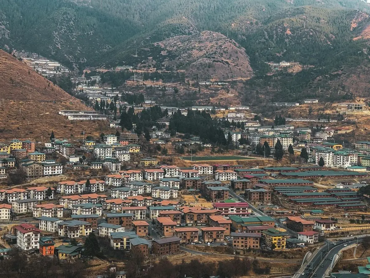 Aerial view of Thimphu city nestled in Bhutan's mountain landscapes, showcasing unique architecture and scenic beauty.