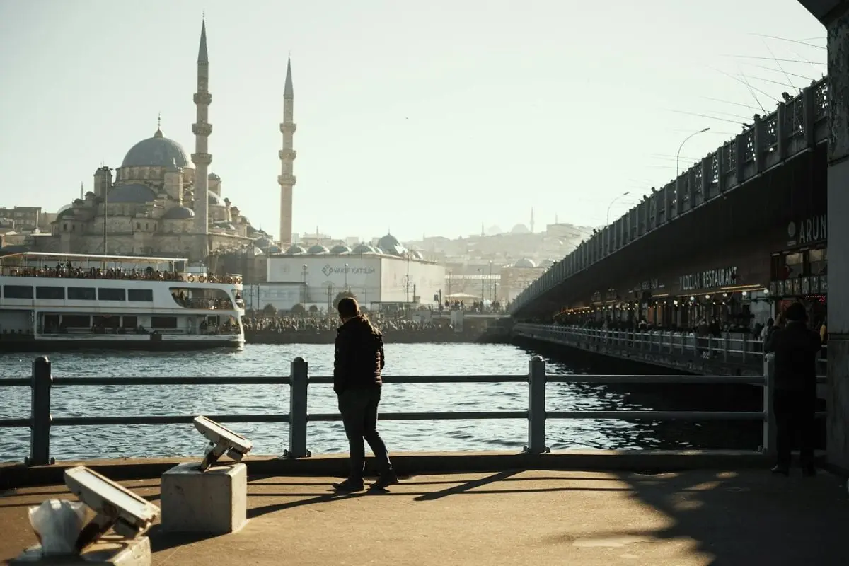A man walking by the iconic Galata Bridge with a view of the mosque in Istanbul.