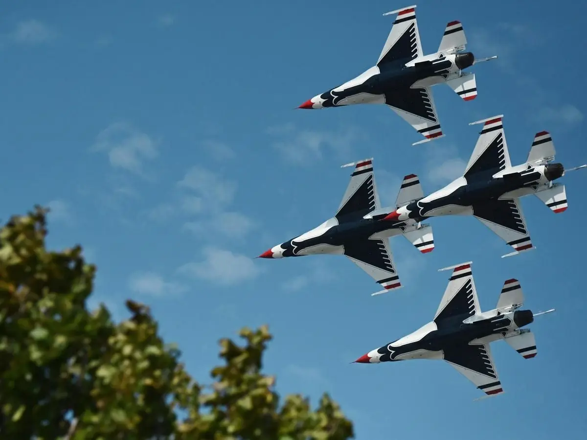 Aerial view of military jets flying in formation against a clear blue sky, showcasing precision.