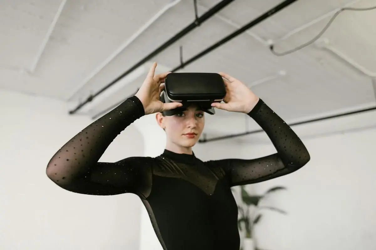 Caucasian woman in black leotard using VR goggles indoors.