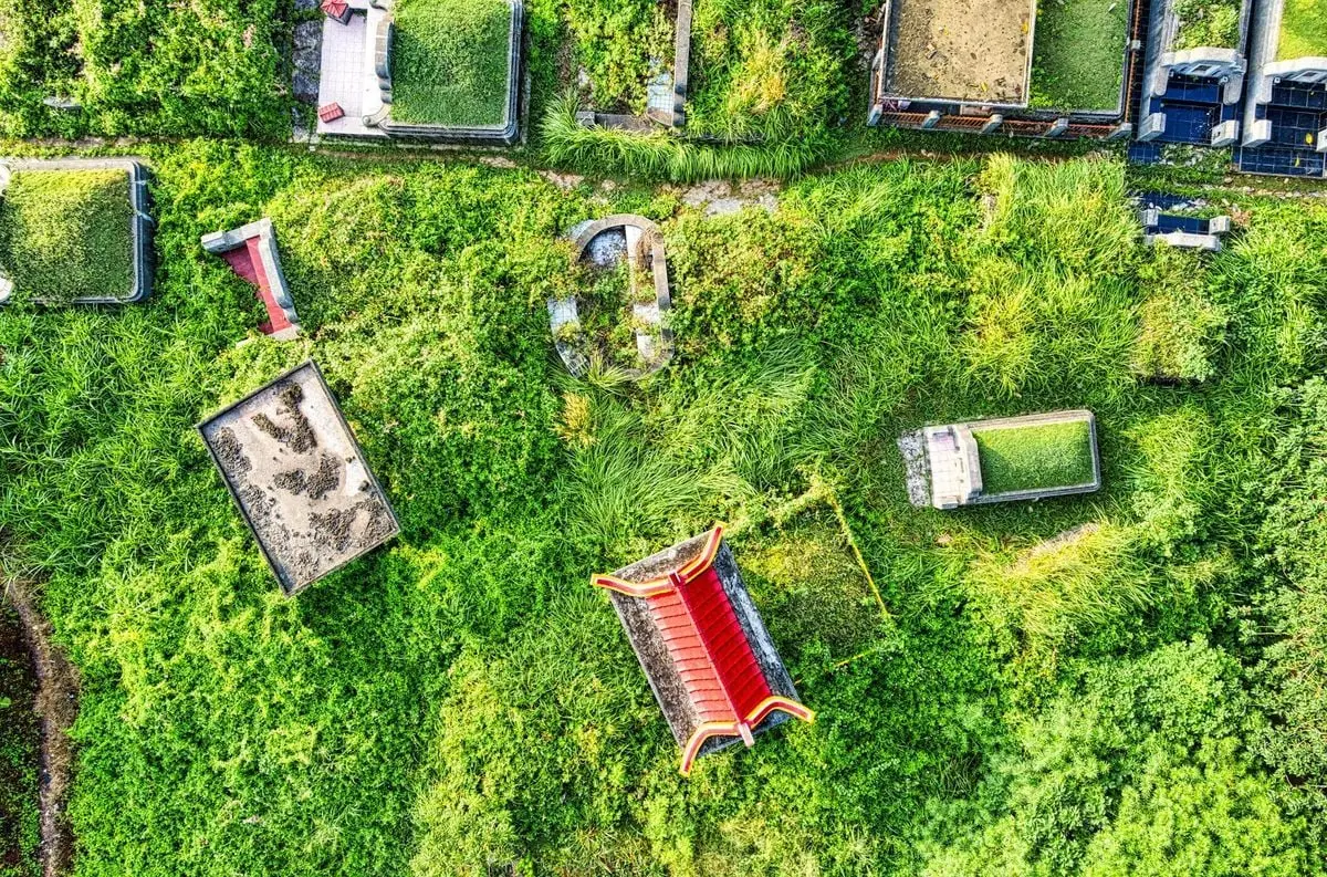 Drone shot of a colorful cemetery in Tangerang, Indonesia, showing green grass and tombs.