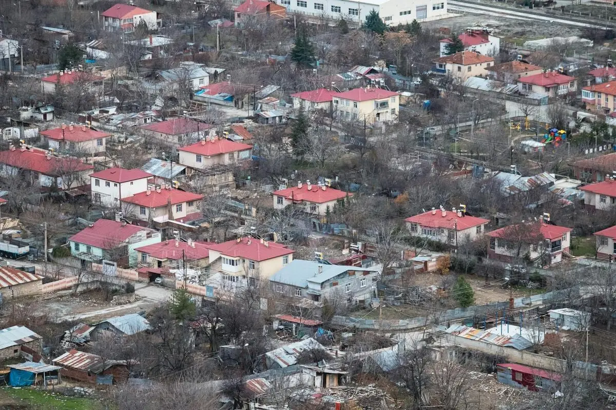 Aerial view of Palu town in Elazığ, Türkiye, showcasing red-roofed houses and surrounding landscape.