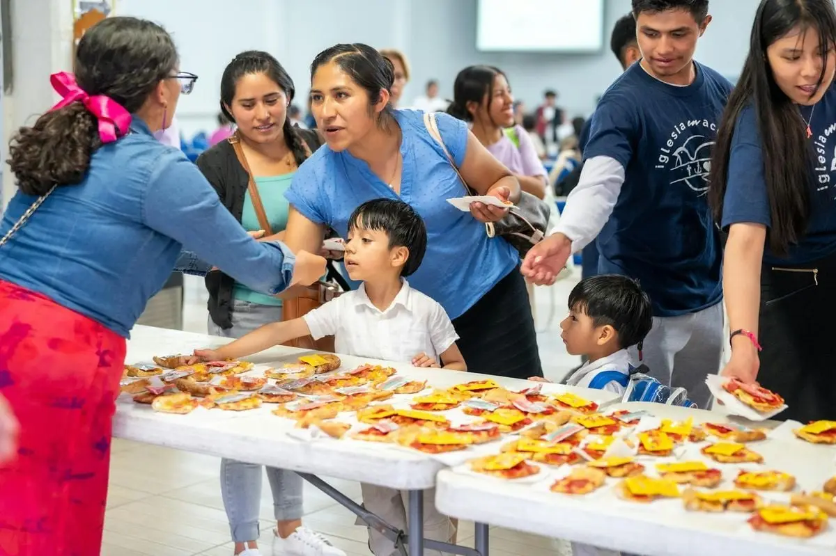 A diverse group enjoying a community event with pizza in Ciudad de México.