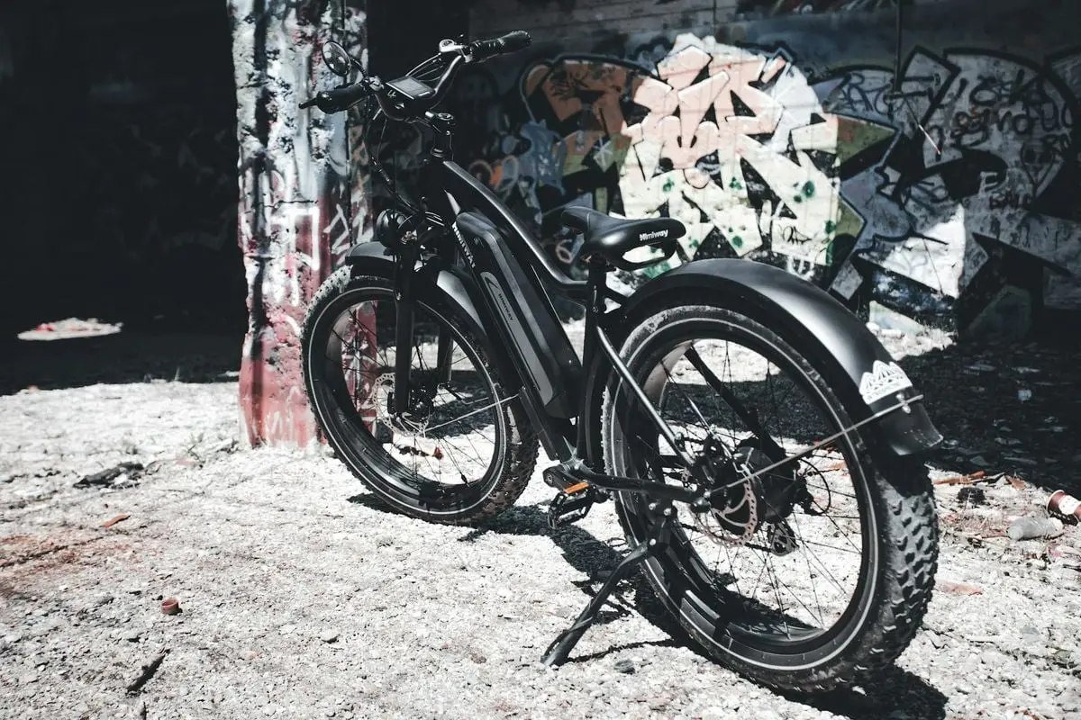 Electric bicycle standing against graffiti wall in urban setting. Eco-friendly transportation concept.