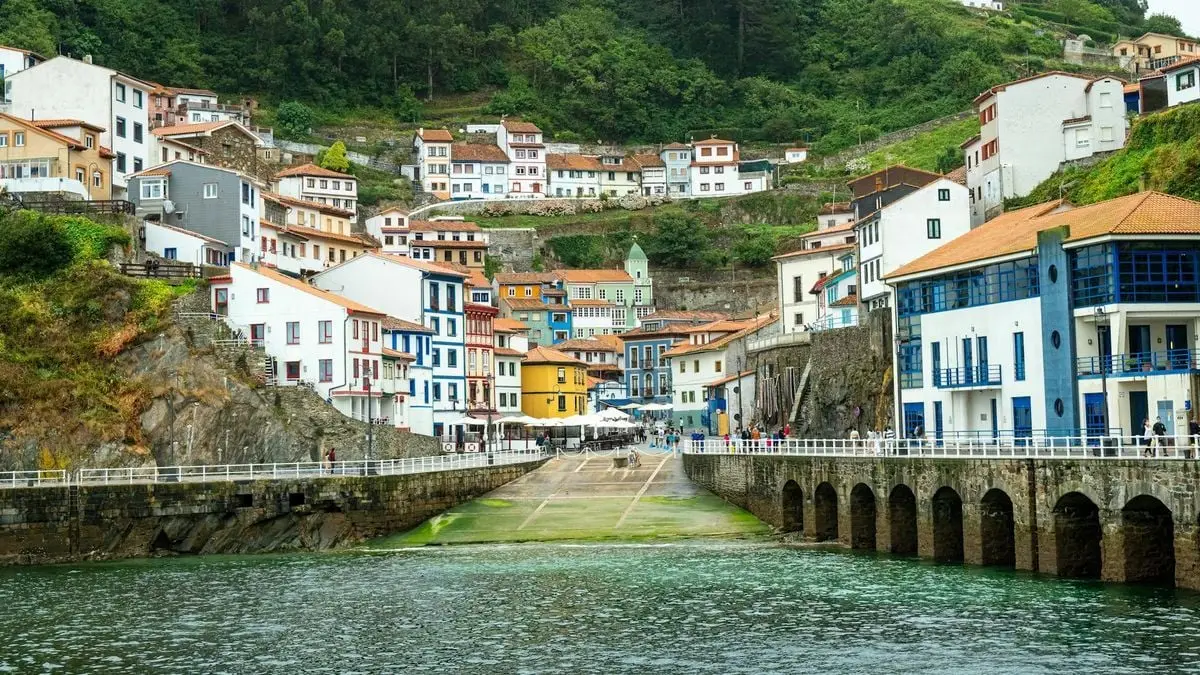 Scenic view of a vibrant coastal town with colorful buildings and lush greenery.