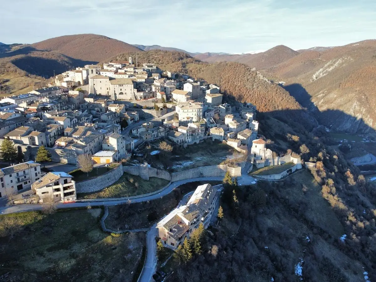 Aerial view of a charming Italian village nestled in rolling hills, showcasing traditional architecture.