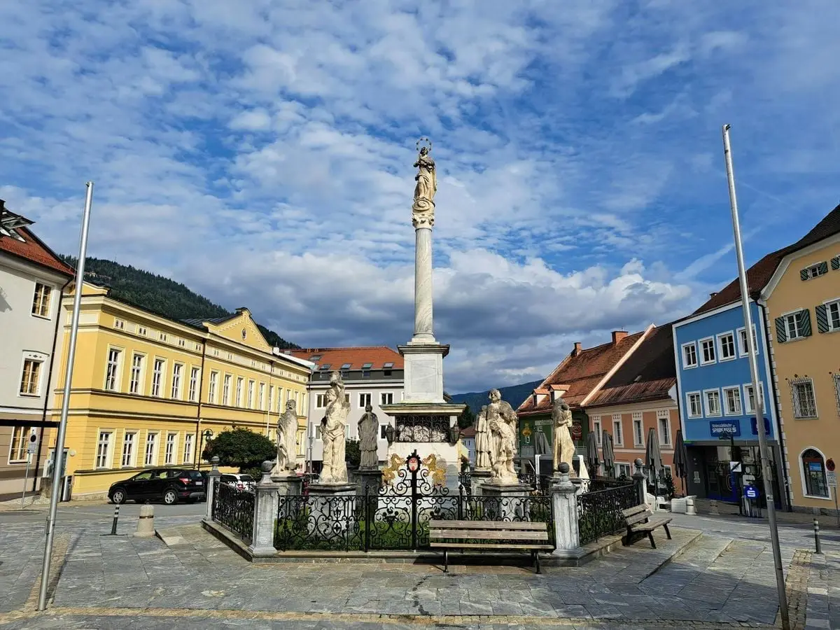 Beautiful town square with statues and colorful buildings in Murau, Austria.