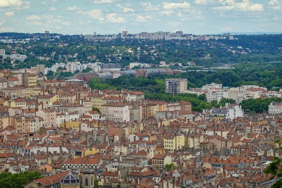 Aerial cityscape of Lyon showcasing dense historic architecture and lush greenery.