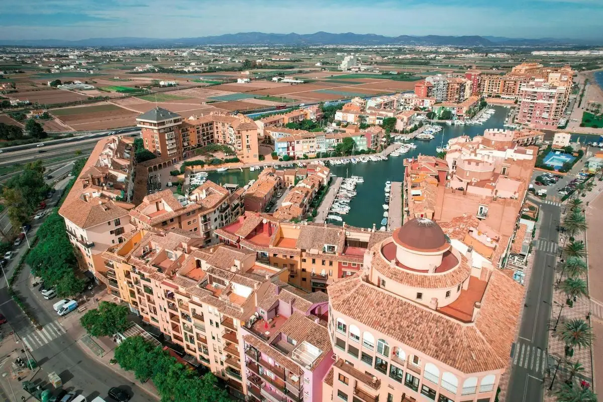 A stunning aerial view of a vibrant coastal town with a marina, showcasing colorful buildings and waterways.