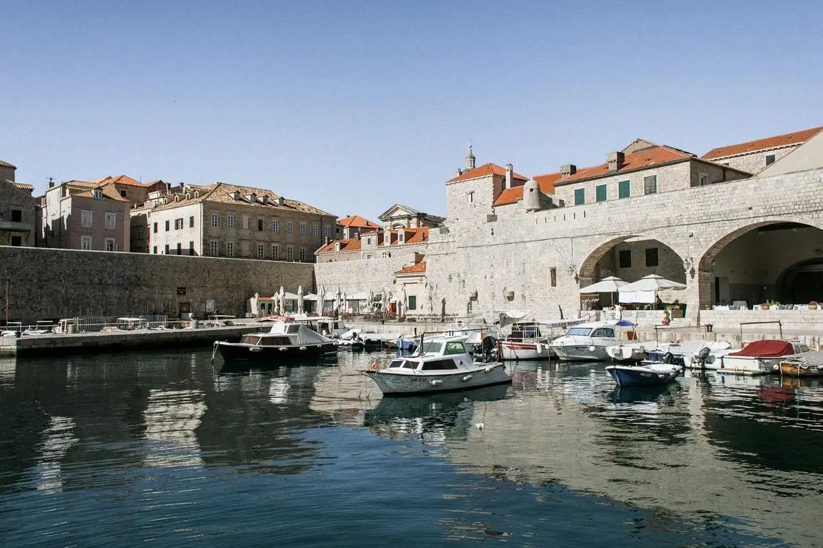 Charming view of Dubrovnik's historic harbor with boats and medieval stone buildings.