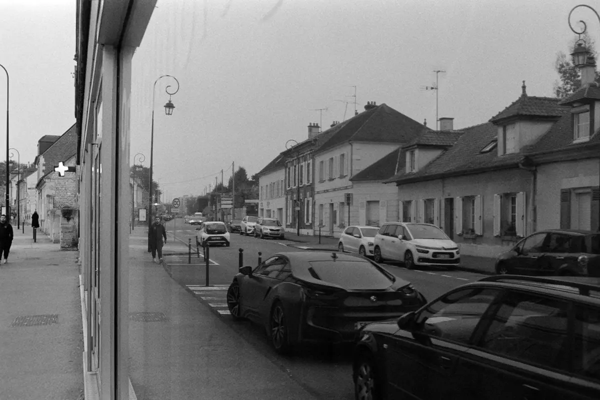 Vintage black and white street photograph capturing Compiègne, France with parked cars and pedestrians.
