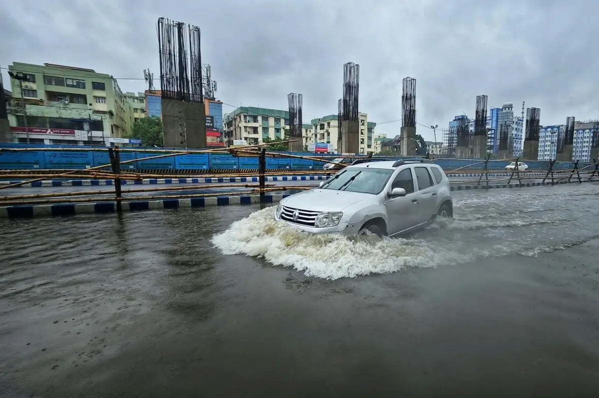 A car navigating through a flooded street in urban Kolkata, India.