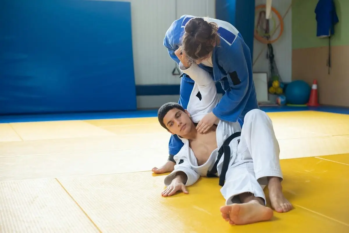 Two judo practitioners engage in training on a tatami mat, showcasing martial arts skills.