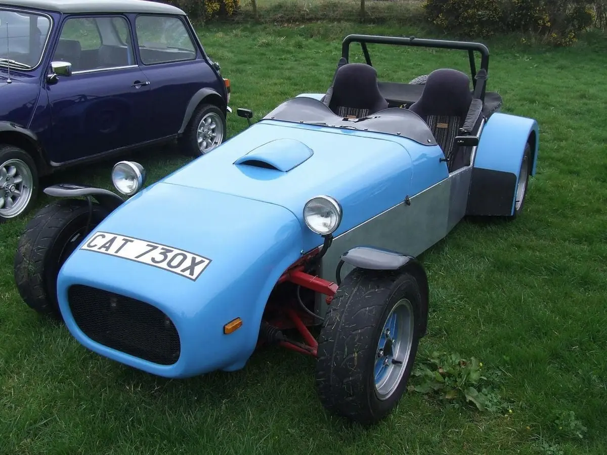 Classic blue roadster and mini cooper parked on grass. Perfect for automotive enthusiasts.