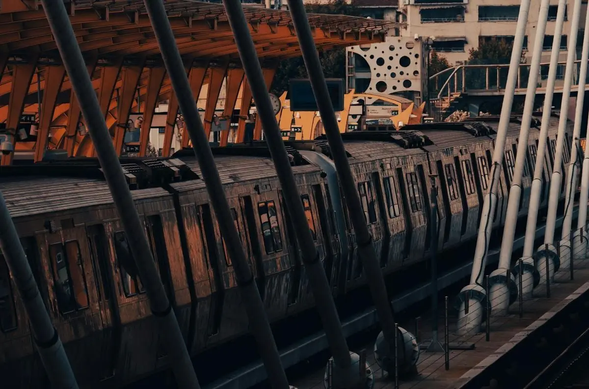 A dynamic view of a passenger train at an urban railway station with striking architecture.