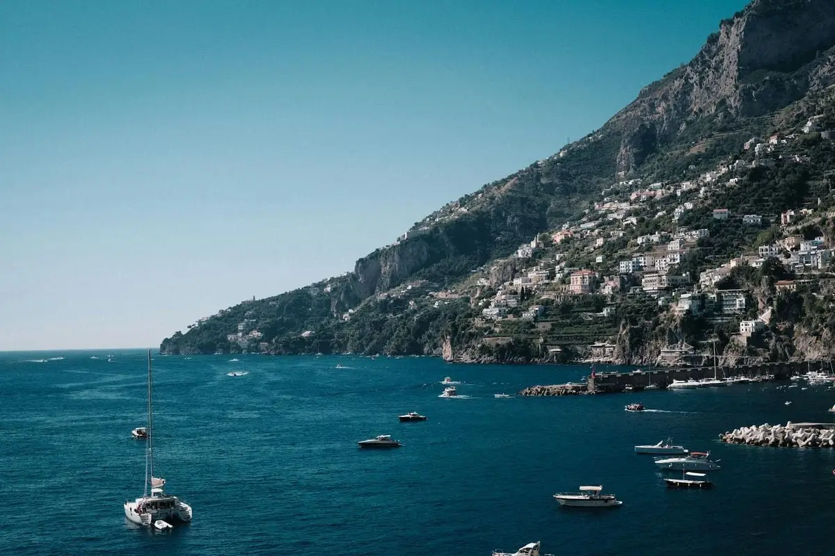 A stunning view of the Amalfi coastline featuring boats and rugged cliffs under a clear sky.
