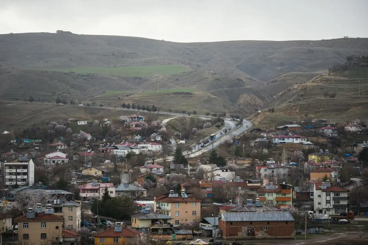 A picturesque view of Palu village in Elazığ, Türkiye, nestled between rolling hills under a cloudy sky.