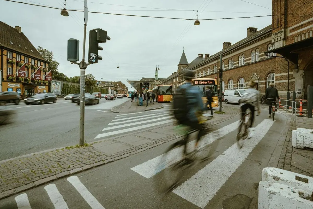 Cyclists ride through a bustling urban intersection in a European city with historical architecture.
