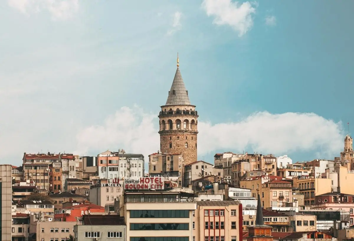 Scenic view of Galata Tower amidst the vibrant Istanbul cityscape under a blue sky.