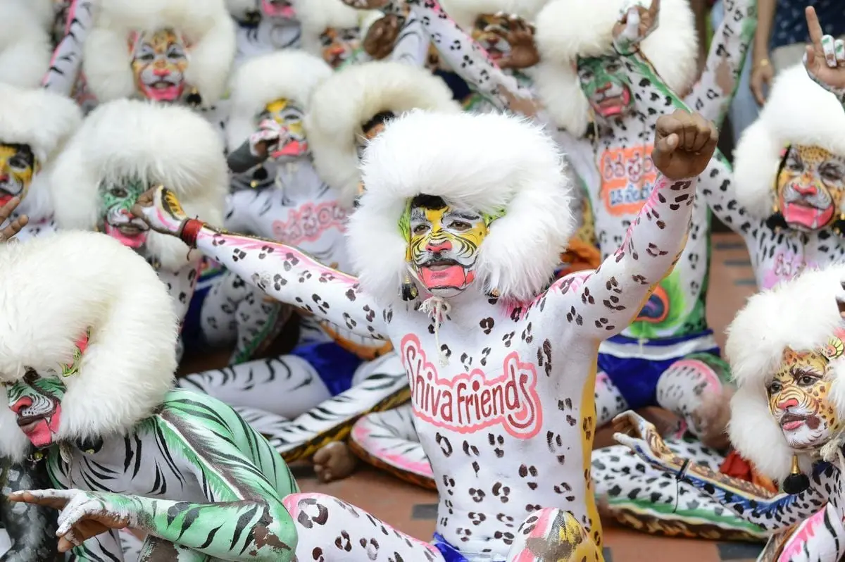 Vibrant festival scene with performers in detailed face paint and costumes celebrating together.