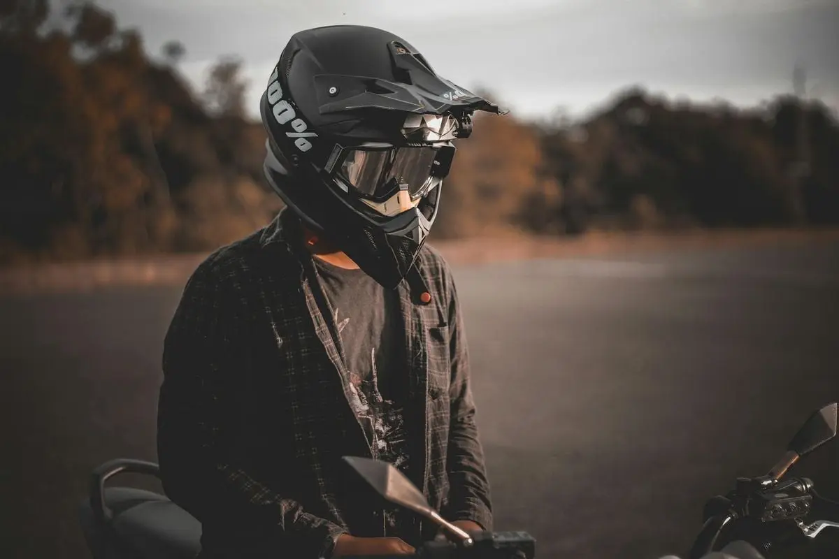Motorcyclist wearing full-face helmet, enjoying a scenic outdoor ride at sunset.