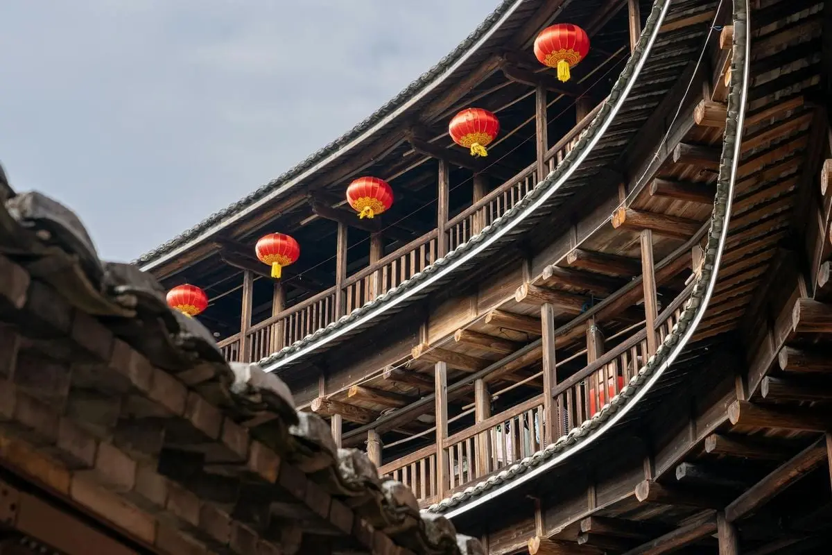 Wooden tulou structure adorned with red lanterns, symbolizing traditional Chinese architecture.