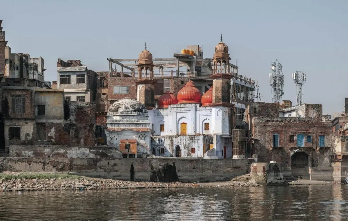 View of historic buildings with red domes along Yamuna riverbank in Mathura, Uttar Pradesh, India.