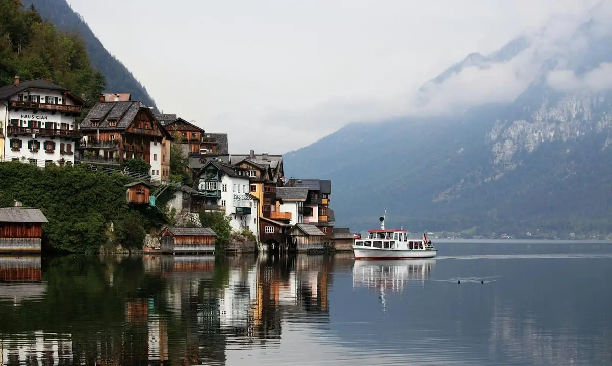 Charming lakeside view of Hallstatt, Austria with reflections of traditional houses and a boat.