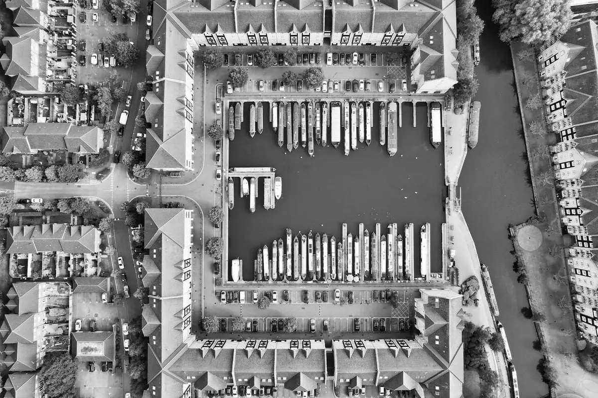 Black and white aerial view of marina with moored boats in Hertfordshire, showcasing geometric urban layout.