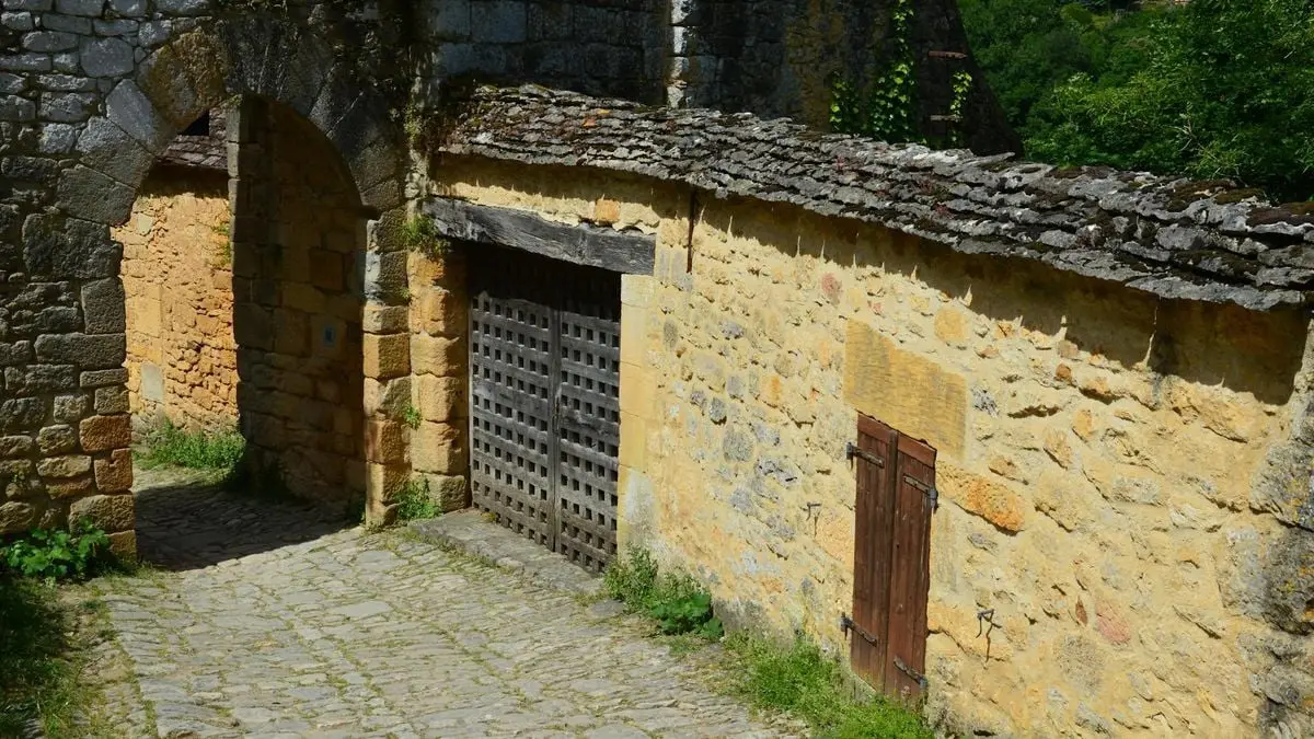 A serene view of a stone archway and historic building with wooden gate, evoking a sense of history.
