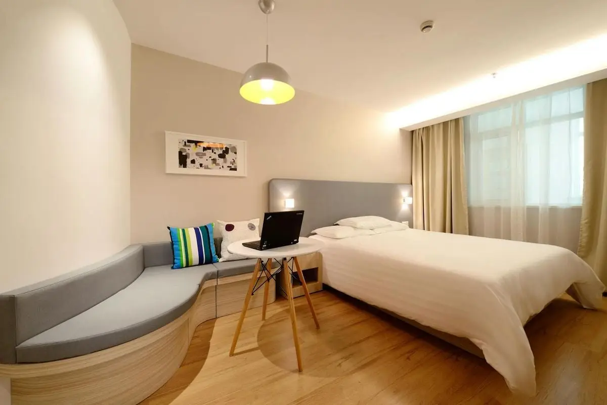 Modern hotel room featuring a bed, laptop, and stylish decor with ample lighting.