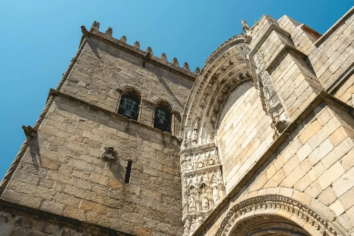 Gothic architecture of a cathedral tower against a clear blue sky in Guimarães, Portugal.