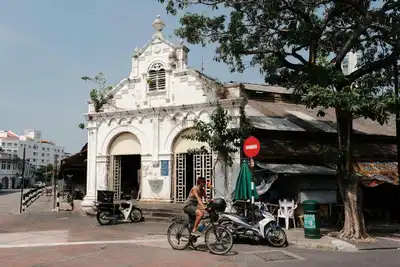 A cyclist passes the historic Campbell Street Market in George Town, Penang, blending colonial architecture with urban life.