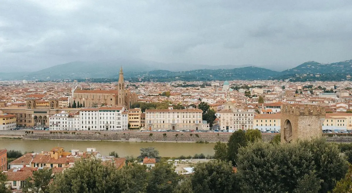 Scenic view of Florence with historic architecture and Arno River under a cloudy sky.