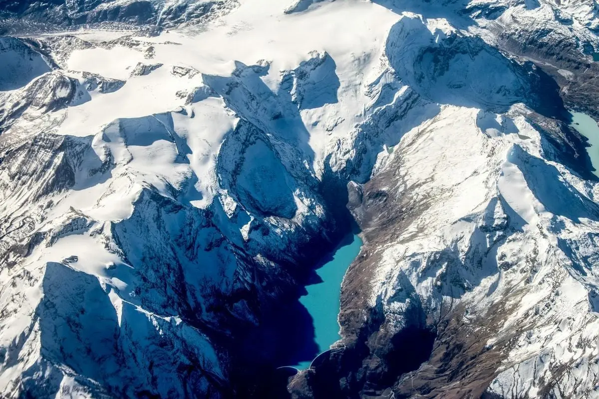 Explore the breathtaking aerial view of snow-covered peaks and icy blue lakes in winter.