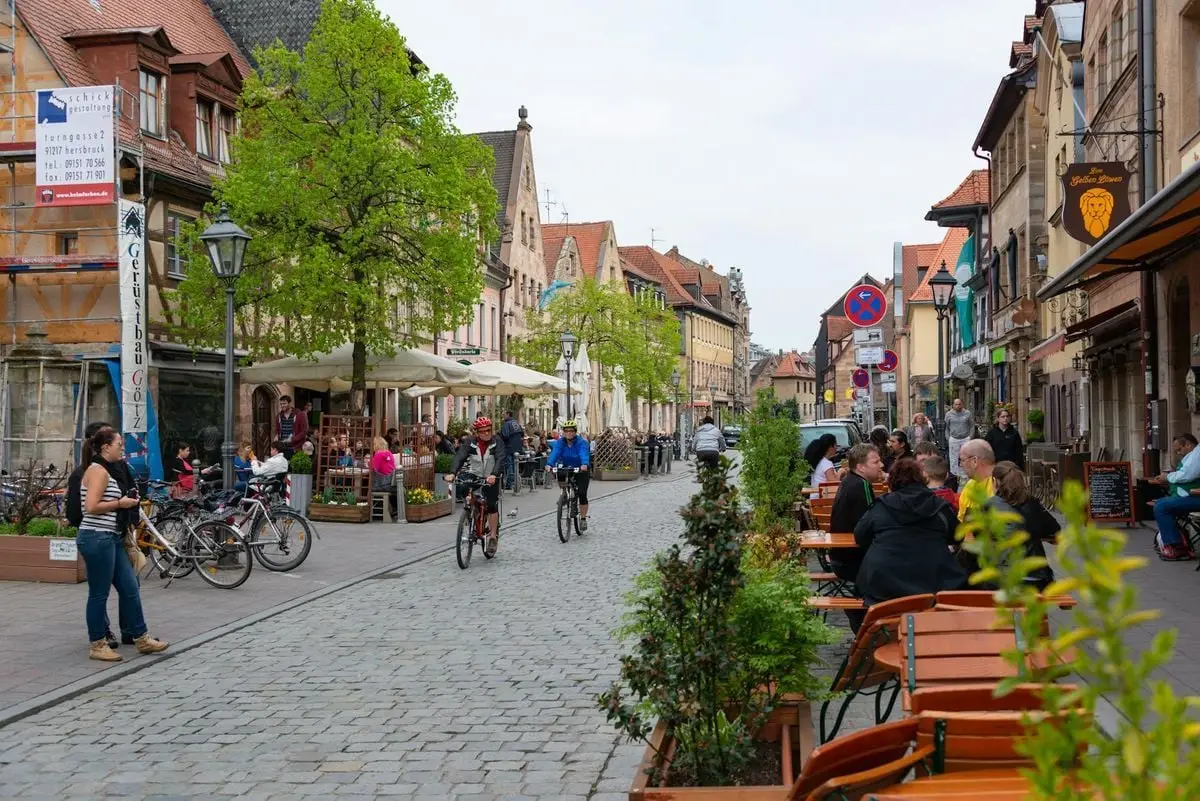 Bicyclists and people enjoying a quaint street café in historic Fürth, Germany.