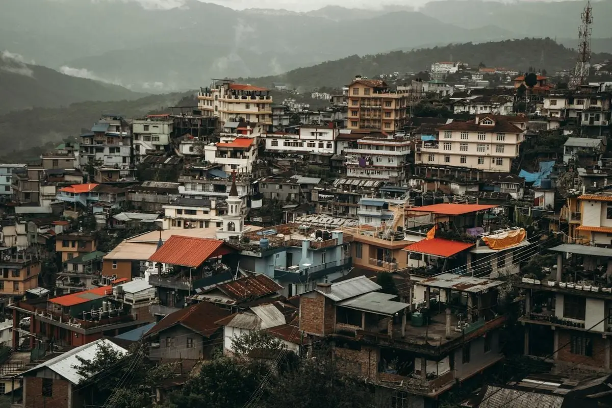 Aerial view of a densely populated urban area with colorful rooftops and residential buildings amidst mountains.