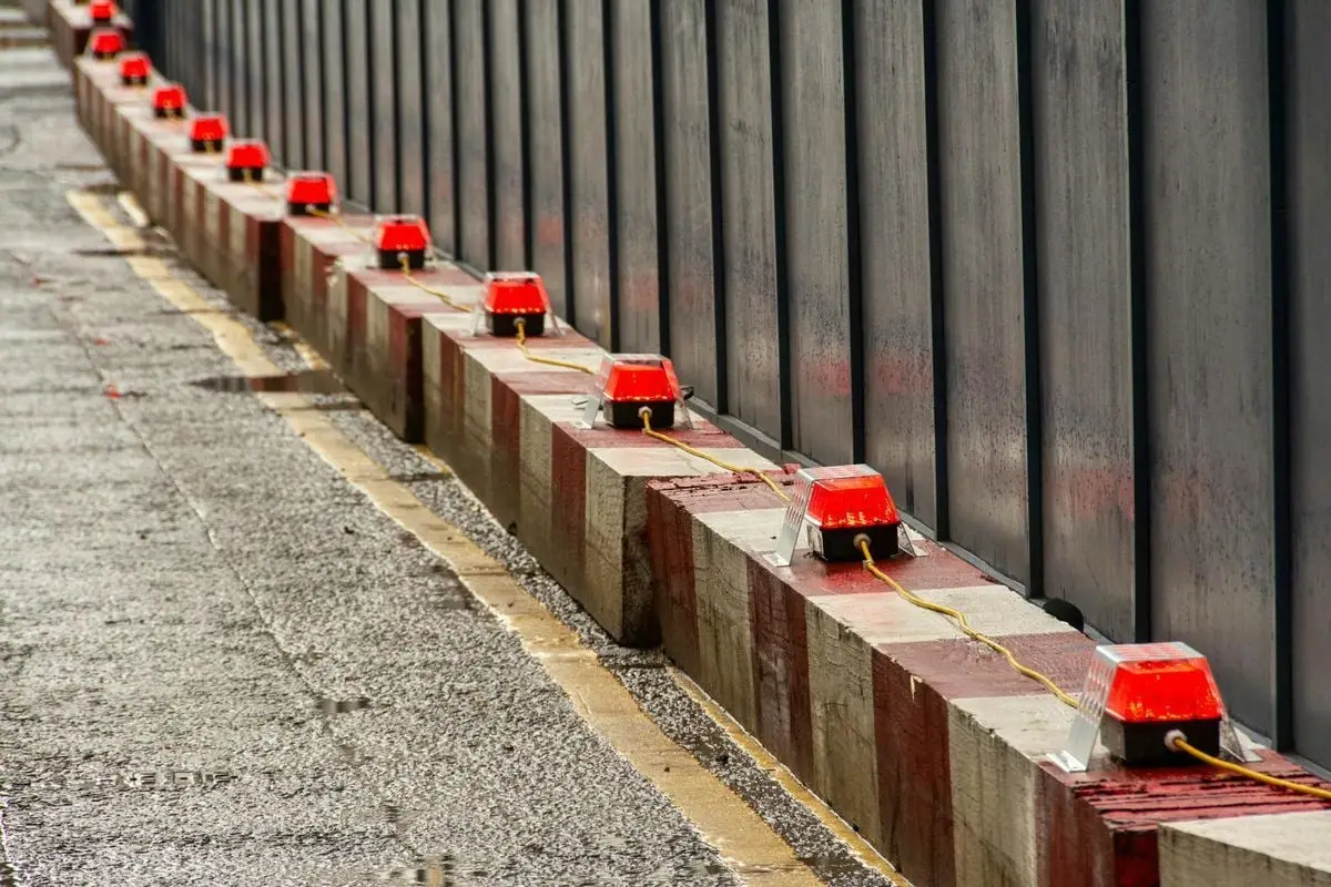 Row of red warning lights on construction barriers. Urban setting.
