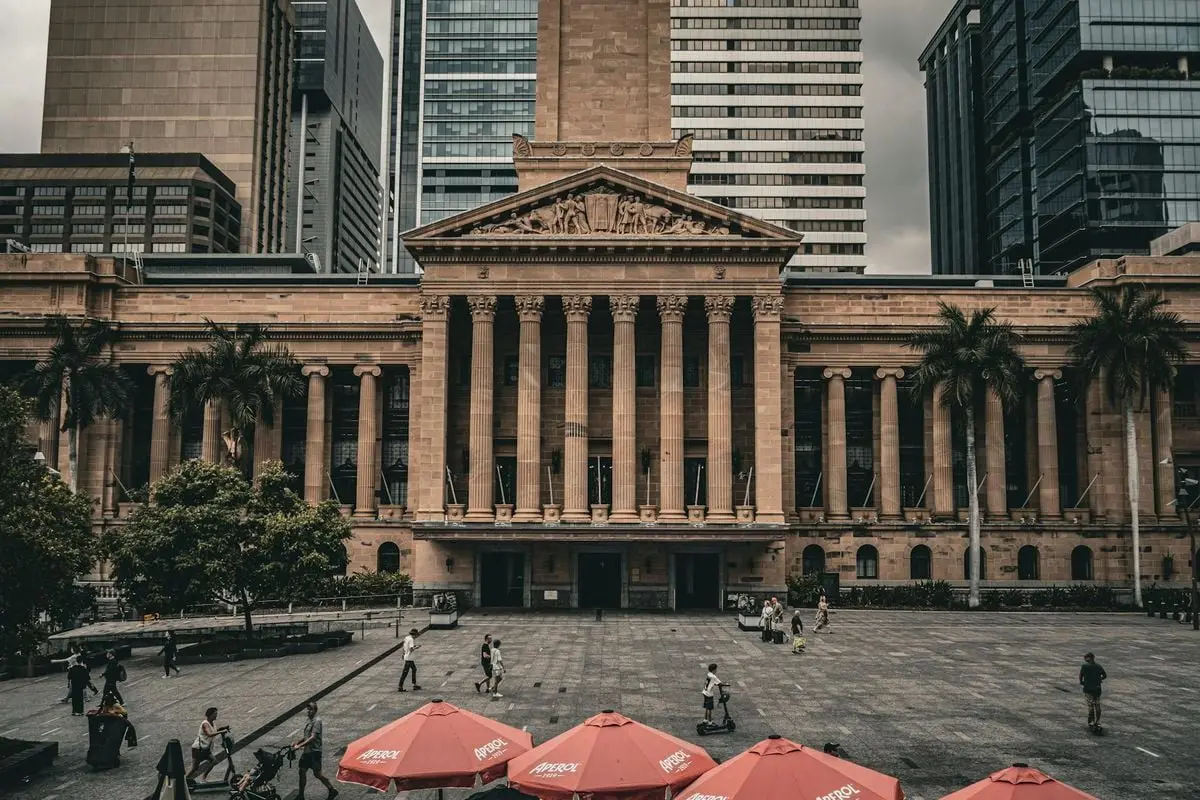 A view of Brisbane City Hall with urban surroundings and pedestrians in the plaza.