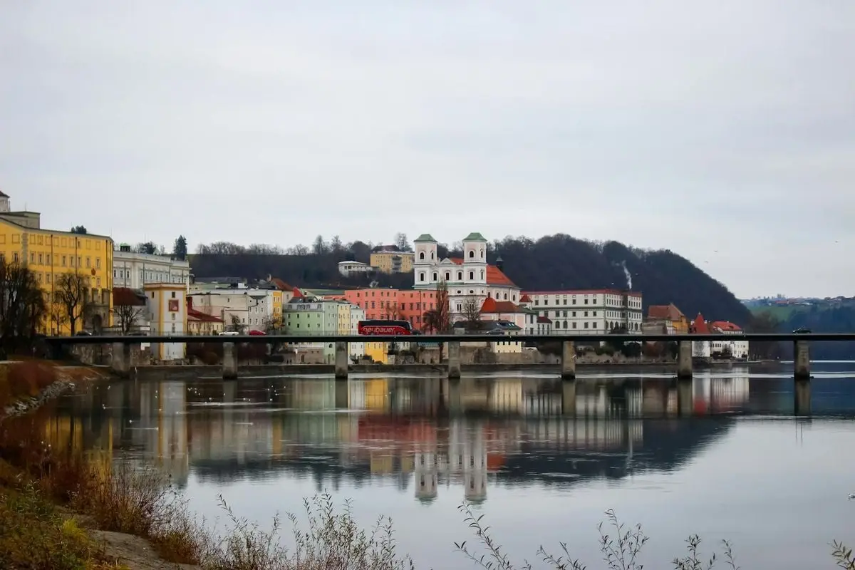 Scenic view of a riverfront European town with colorful buildings reflected in calm waters.