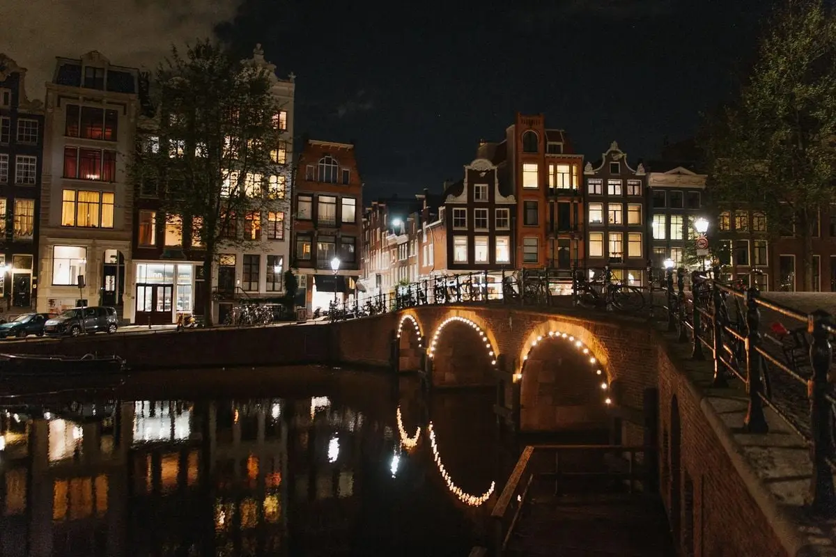 Beautiful illuminated bridge and houses along Amsterdam's canal at night.