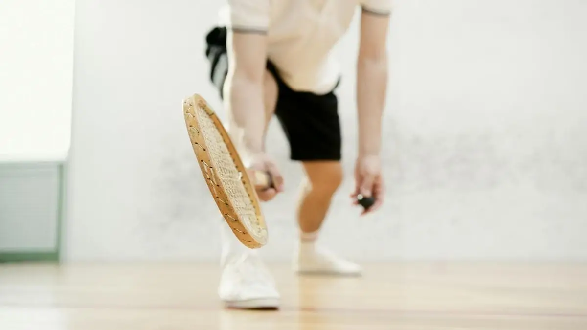 Close-up of a squash player swinging their racket indoors with dynamic motion.