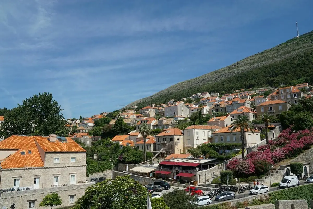 Charming hillside view of orange-roofed buildings in Dubrovnik, Croatia under a clear blue sky.