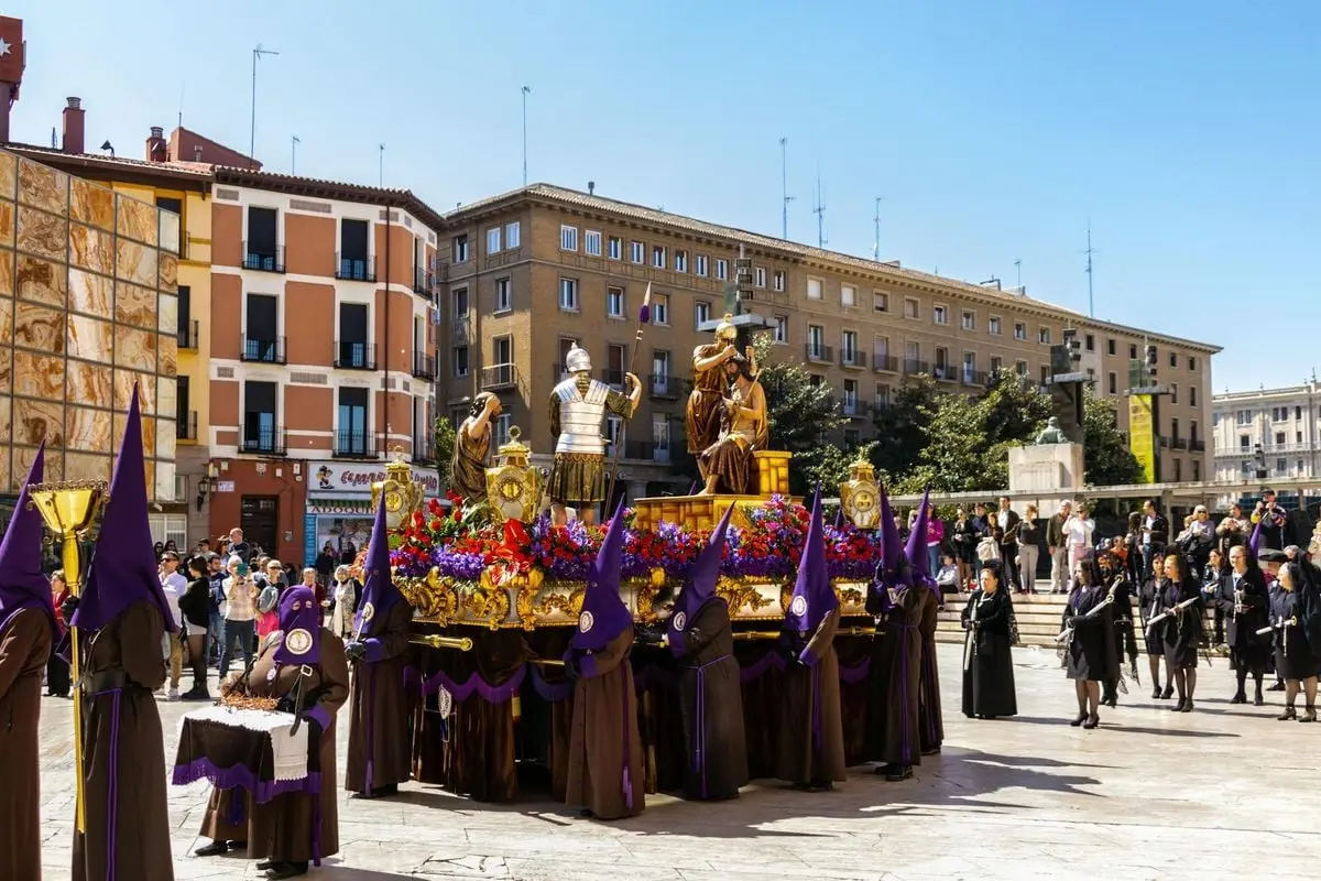 A vibrant religious procession with costumes and statues in Zaragoza, Spain.