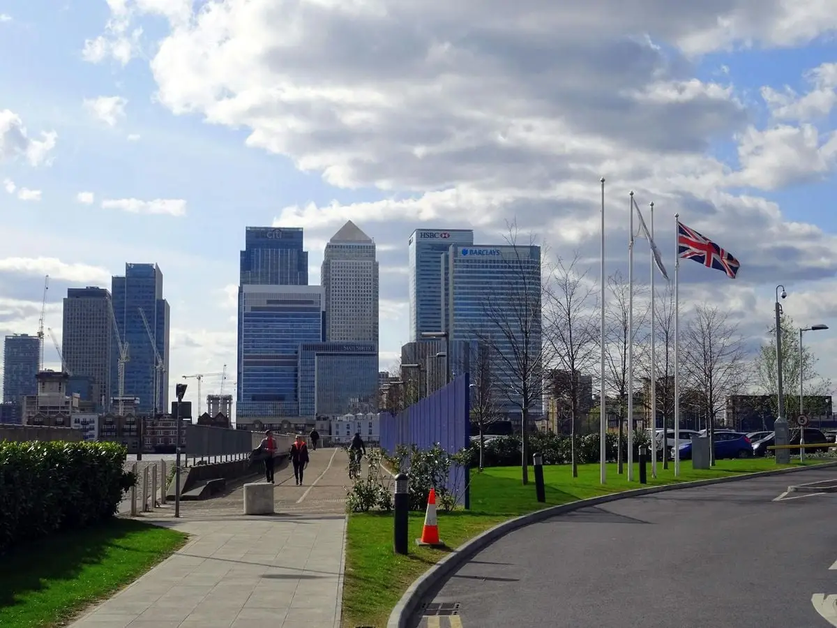 A view of the Canary Wharf skyscrapers in London, UK with a Union Jack flag in the foreground.