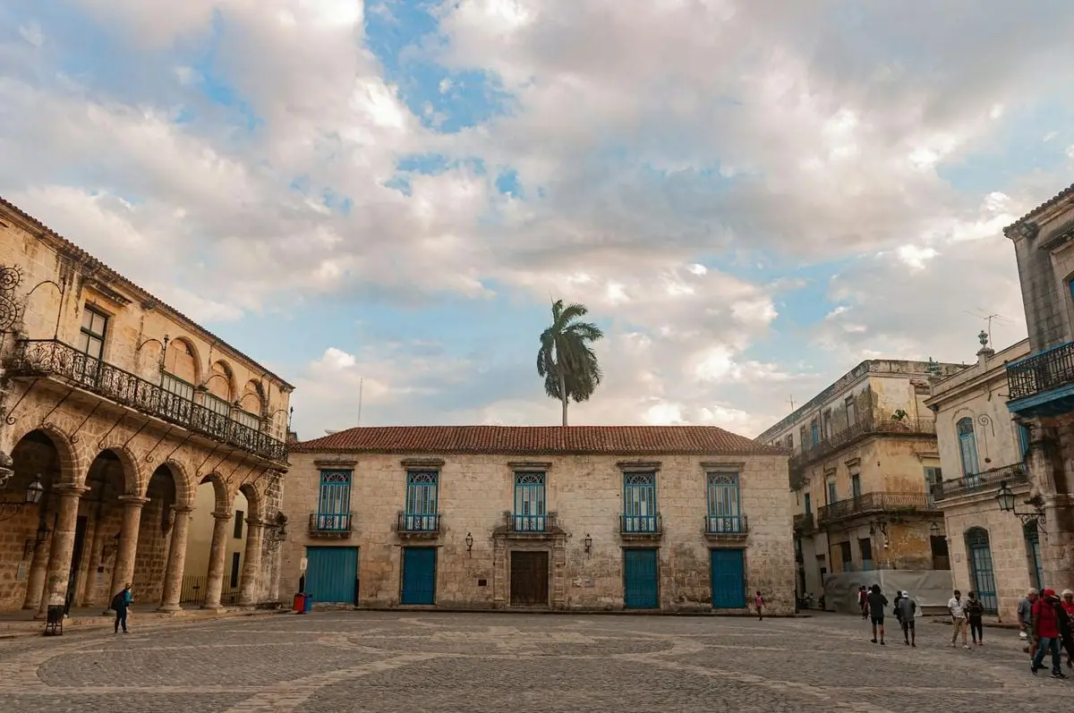 Scenic view of a historic square in Old Havana, featuring colonial architecture and vibrant blue doors.