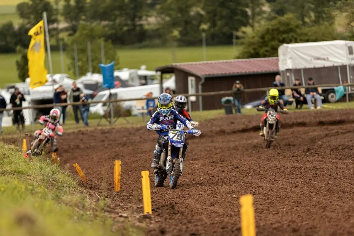 Action-packed dirt bike race on a muddy track with multiple riders competing outdoors.