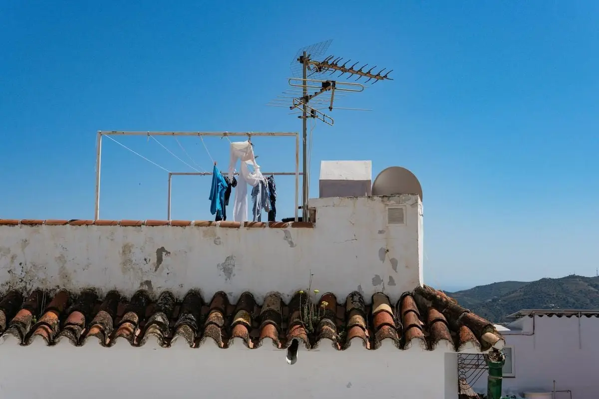 Rustic rooftop in Frigiliana, Spain with clothesline under clear sky showcasing traditional Spanish architecture.