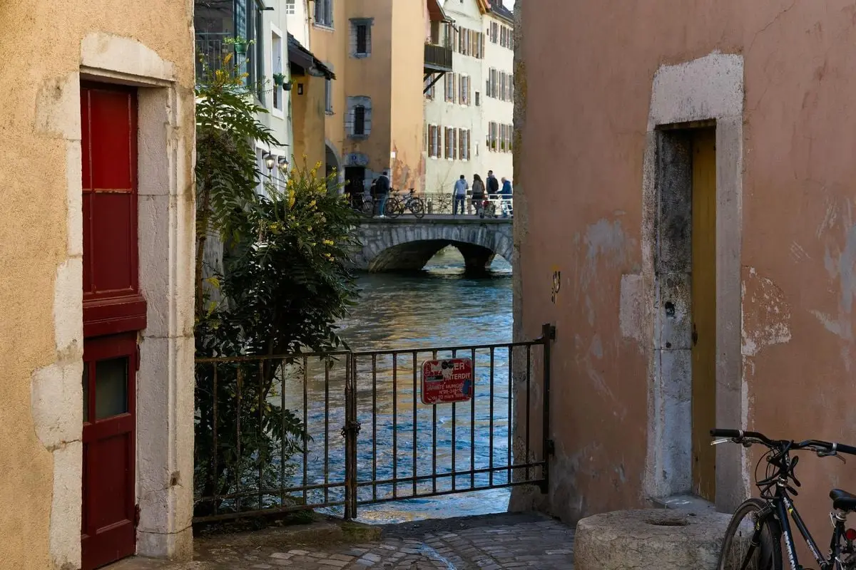 Picturesque canal scene in Annecy's historic district with a stone bridge and colorful buildings.