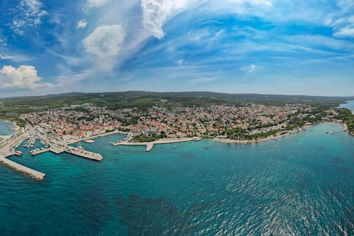Panoramic aerial view of a scenic coastal town with bustling harbor and clear blue waters.